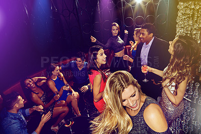 Buy stock photo Shot of a group of young adults enjoying themselves while out in a nightclub