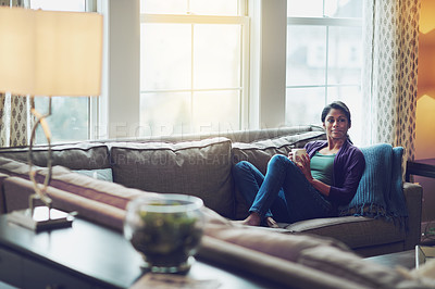 Buy stock photo Woman, coffee and relax on sofa by window with memory, thinking and start morning in living room. Indian person, tea cup or drink on couch with decision, perspective and reflection in lounge at house