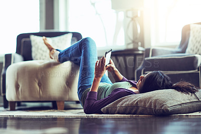 Buy stock photo Woman, phone and texting on floor in home, reading and scroll on mobile app in living room. Girl, smartphone and lying with pillow for notification, contact and relax on carpet with social network