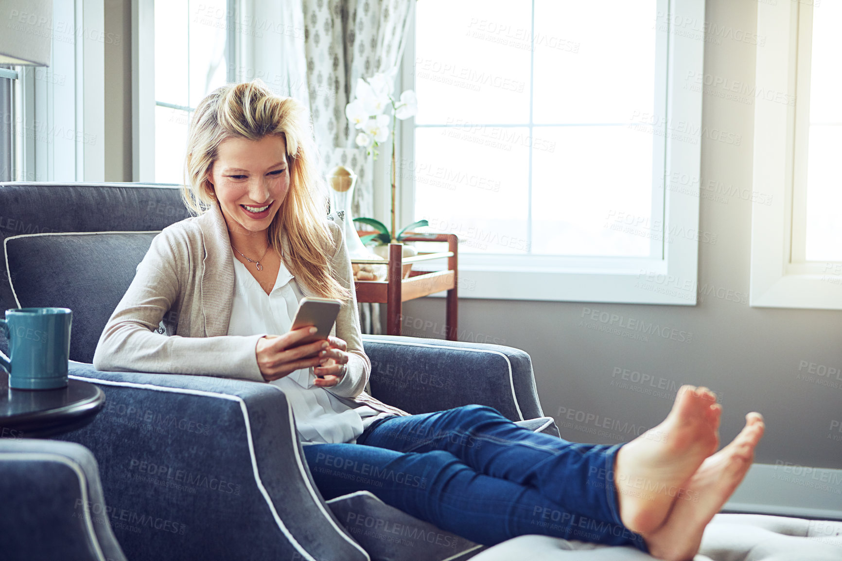 Buy stock photo Shot of a young woman using a mobile phone on the sofa at home