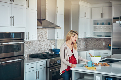 Buy stock photo Shot of a young woman using a digital tablet while baking at home