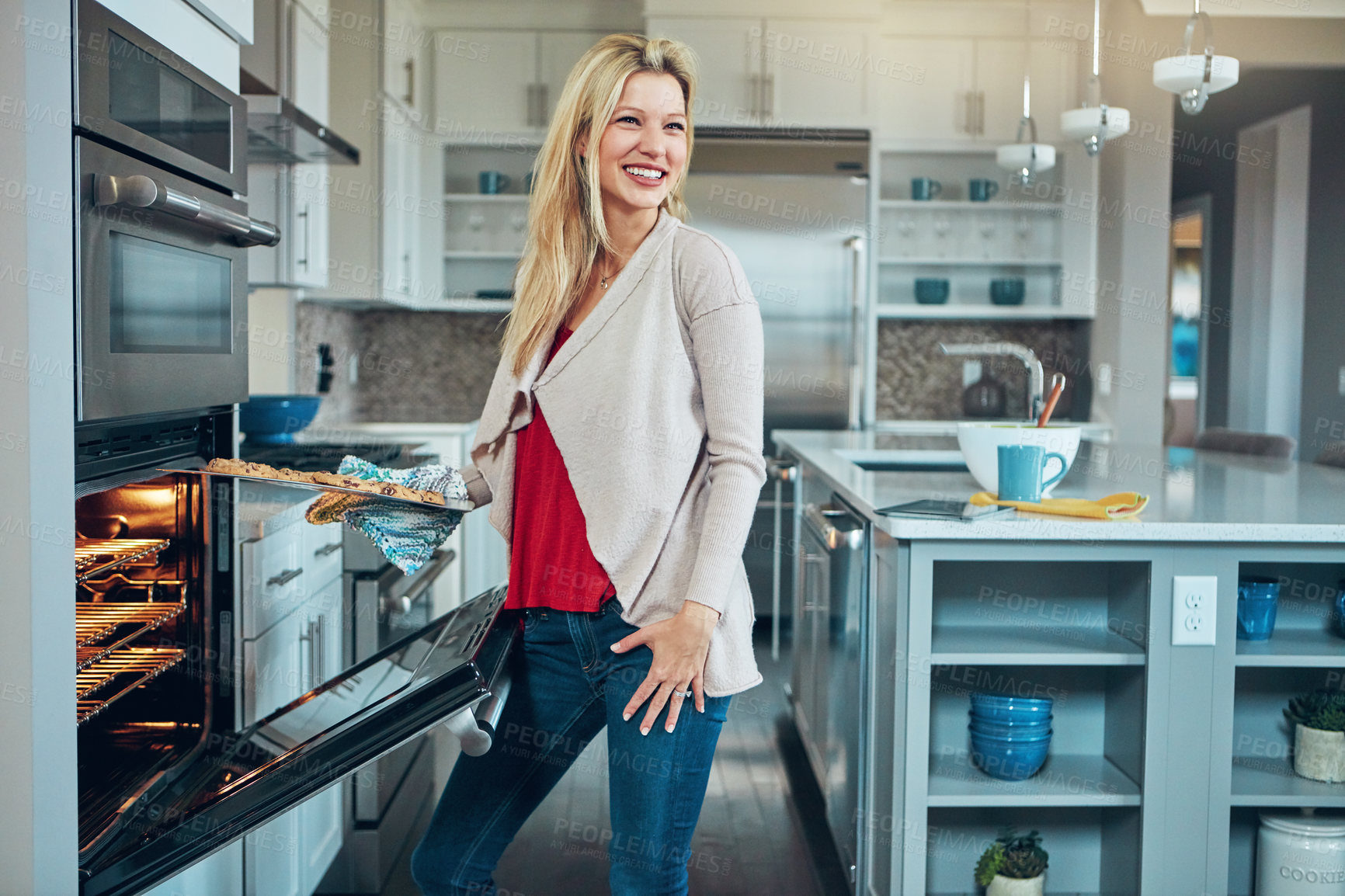 Buy stock photo Shot of a young woman baking chocolate chip cookies at home