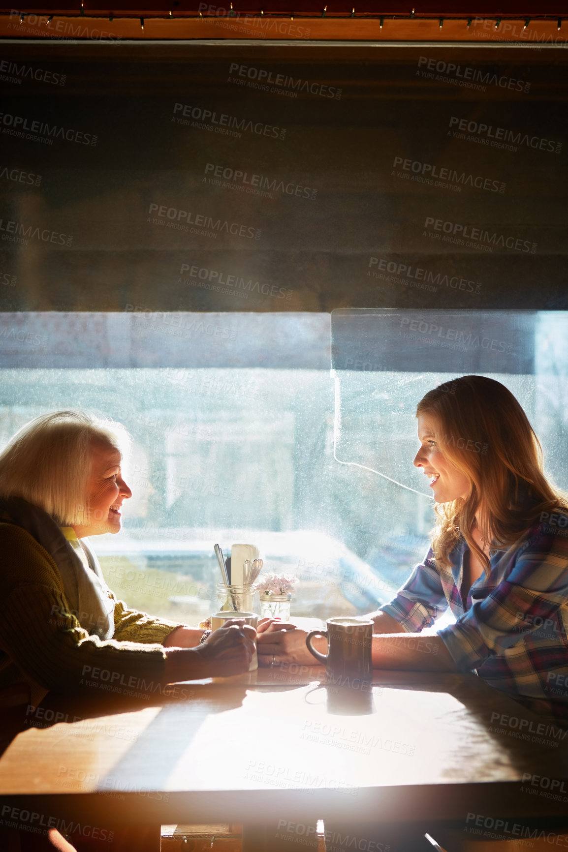 Buy stock photo Shot of a young woman and her senior mother bonding together in a cafe