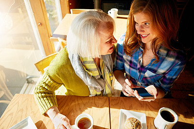 Buy stock photo Senior woman, daughter browsing and smile with smartphone in cafe for social media with memories. Funny, post and restaurant for relaxing with coffee, muffin and sunshine in retirement with excited.