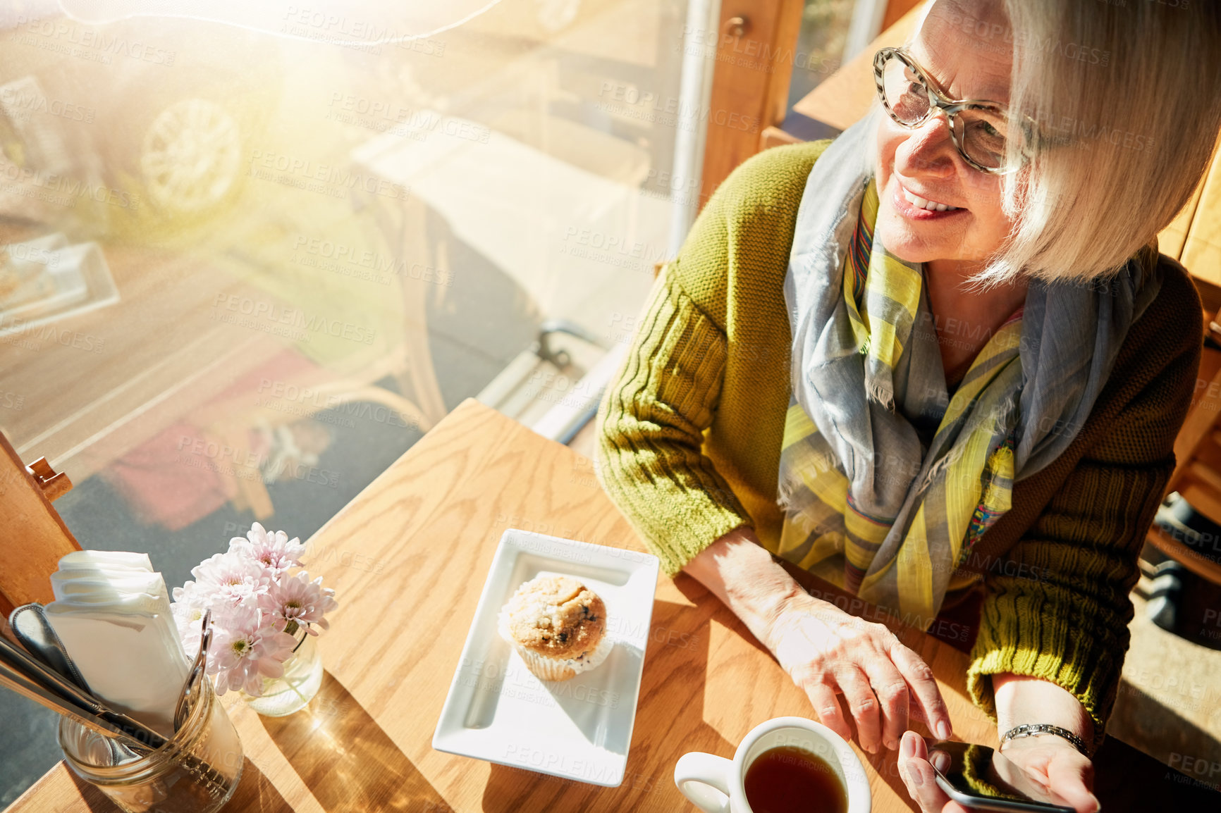 Buy stock photo Shot of a senior woman texting on her cellphone in a cafe