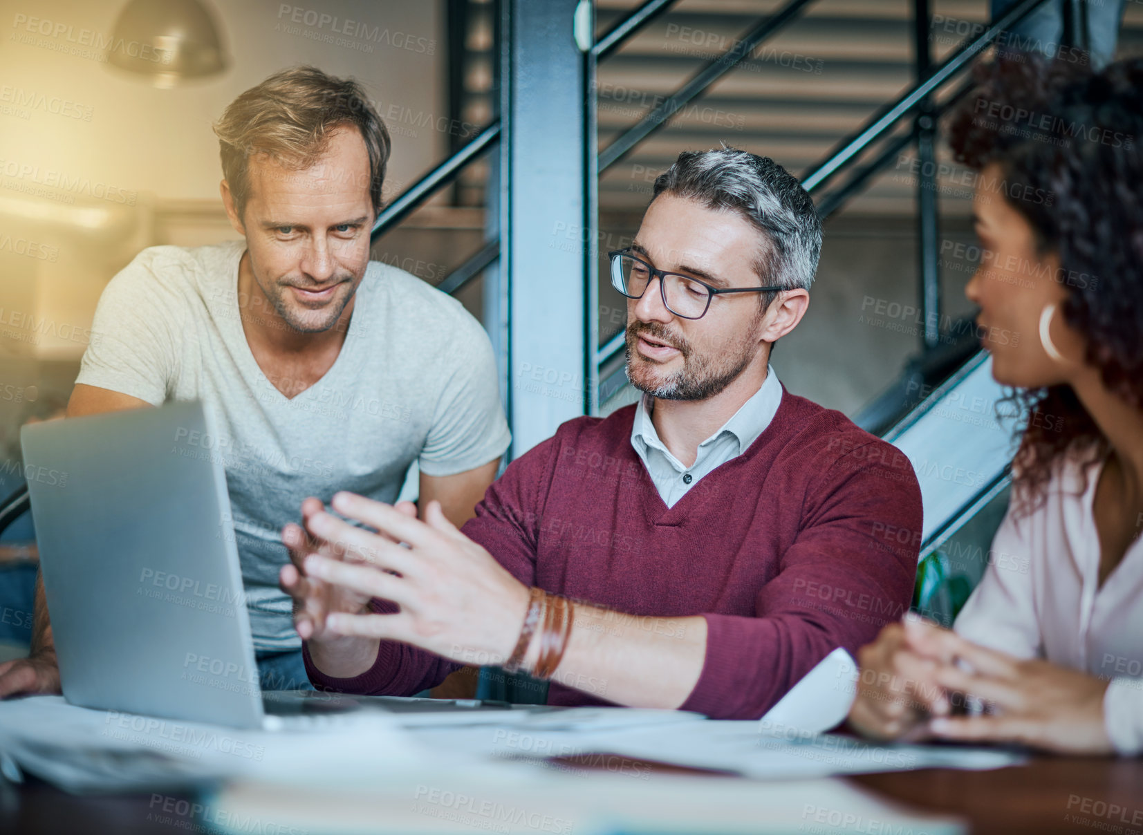 Buy stock photo Shot of a group of businesspeople discussing work related issues around a laptop in the office