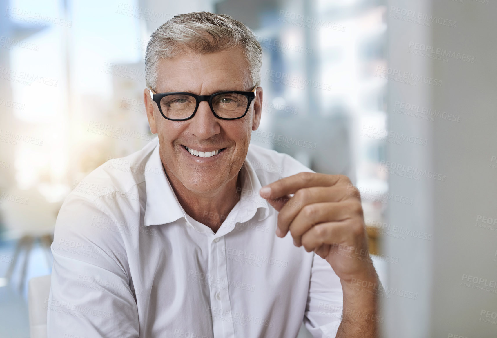 Buy stock photo Shot of a mature businessman with glasses looking into the camera while sitting and working in the office at work