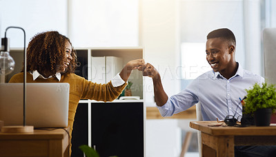 Buy stock photo Shot of two young work colleagues greeting each other with a fist pump while being seated in the office