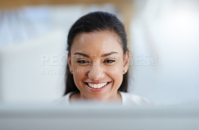 Buy stock photo Shot of a cheerful young businesswoman smiling and working on her computer in the office at work