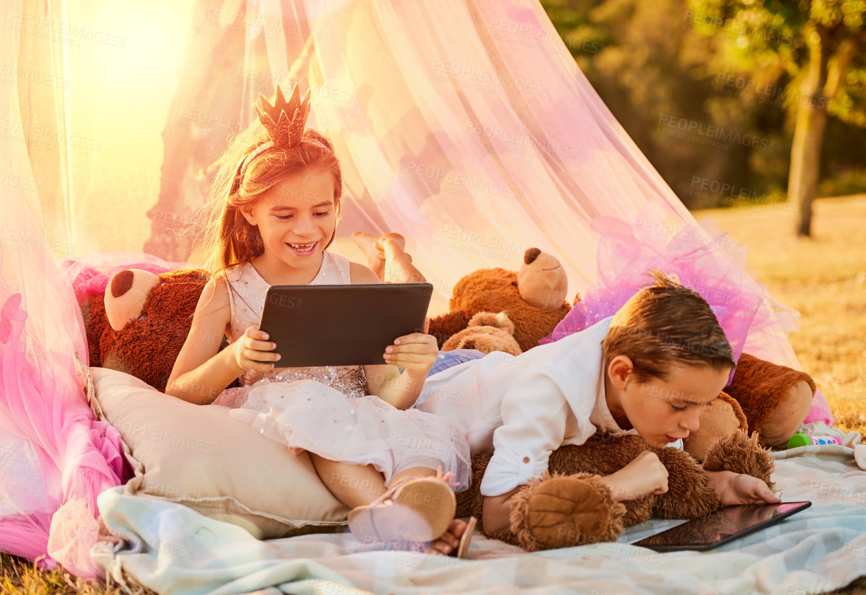 Buy stock photo Shot of an adorable little brother and sister using tablets outdoors