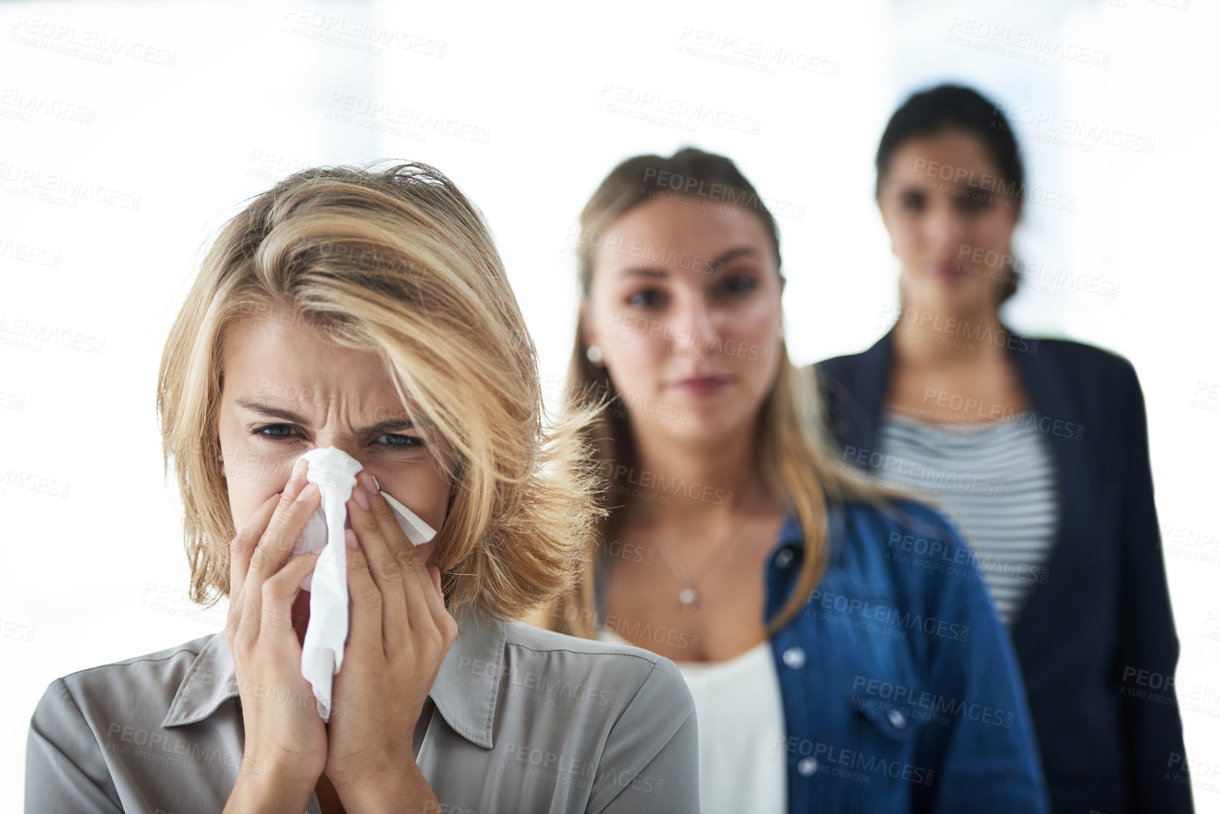 Buy stock photo Shot of a group of businesswomen standing in a row and looking at the camera with one blowing her nose