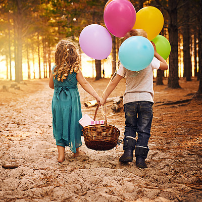 Buy stock photo Shot of an unrecognizable little boy and girl holding a basket and balloons while walking outside in the woods