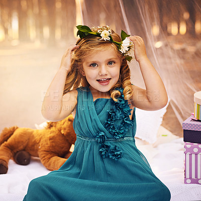 Buy stock photo Shot of a happy little girl looking at the camera and touching a flower crown on her head while sitting outside in the woods