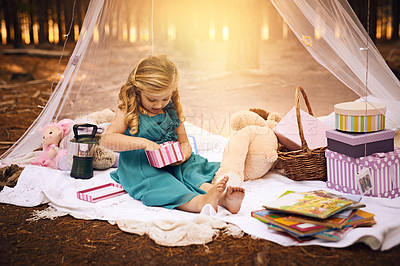 Buy stock photo Shot of a happy little girl opening a little box while sitting on a blanket outside in the woods