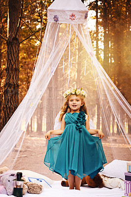Buy stock photo Shot of a happy little girl looking at the camera and holding her beautiful dress wile standing outside in the woods