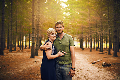 Buy stock photo Shot of a loving couple embracing each other in a hug while standing outside in the woods