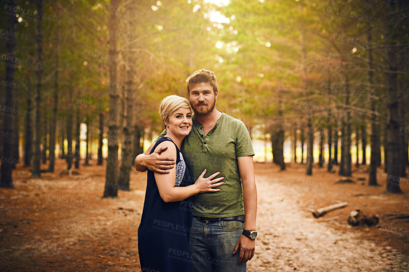 Buy stock photo Shot of a loving couple embracing each other in a hug while standing outside in the woods