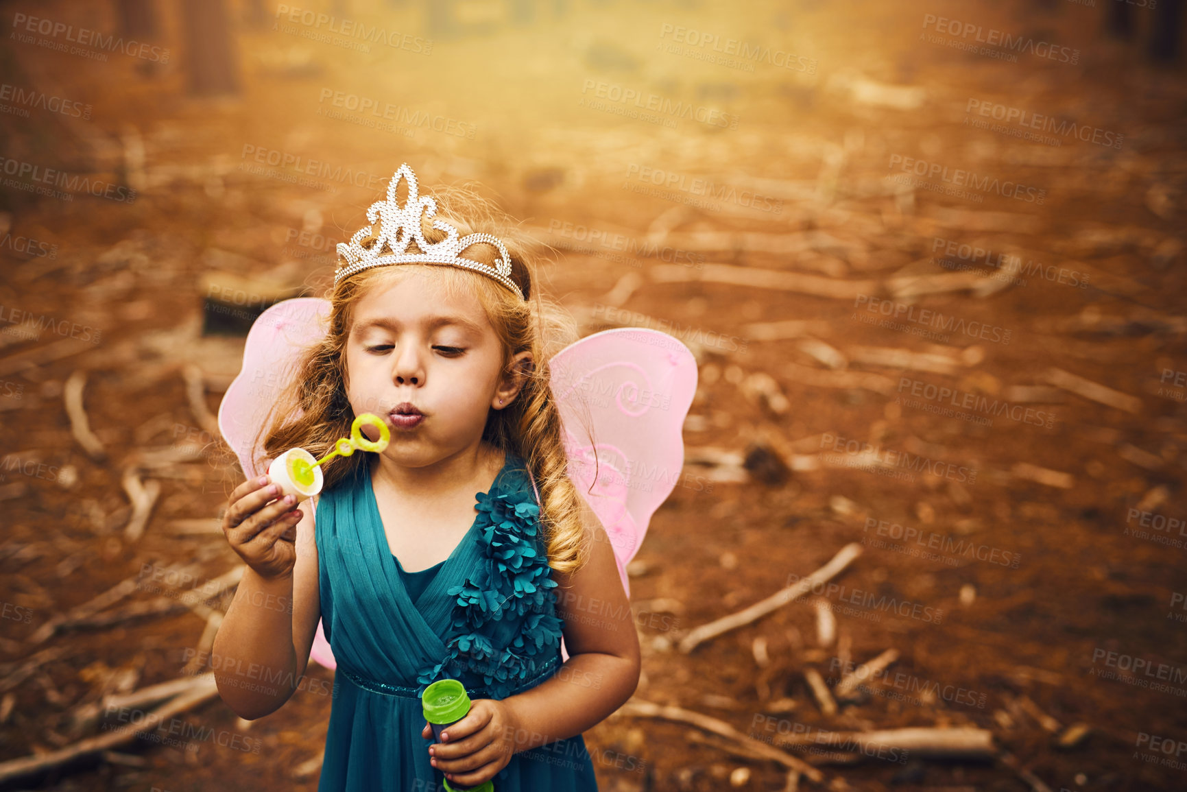 Buy stock photo Shot of a happy little girl blowing bubbles while standing outside in the woods