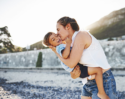 Buy stock photo Shot of a young Mother kissing her son on the cheek at the beach