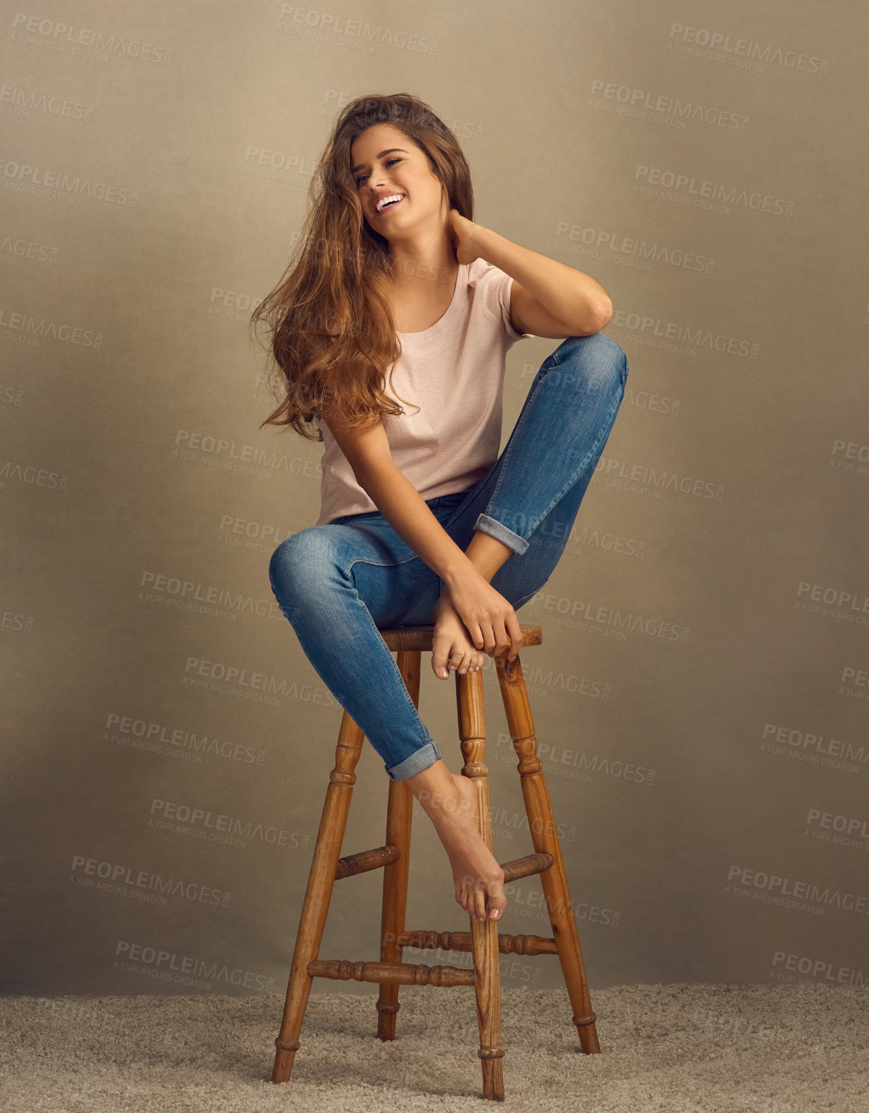 Buy stock photo Studio shot of a beautiful young woman sitting on a stool against a plain background