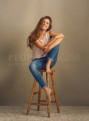 Buy stock photo Studio shot of a beautiful young woman sitting on a stool against a plain background