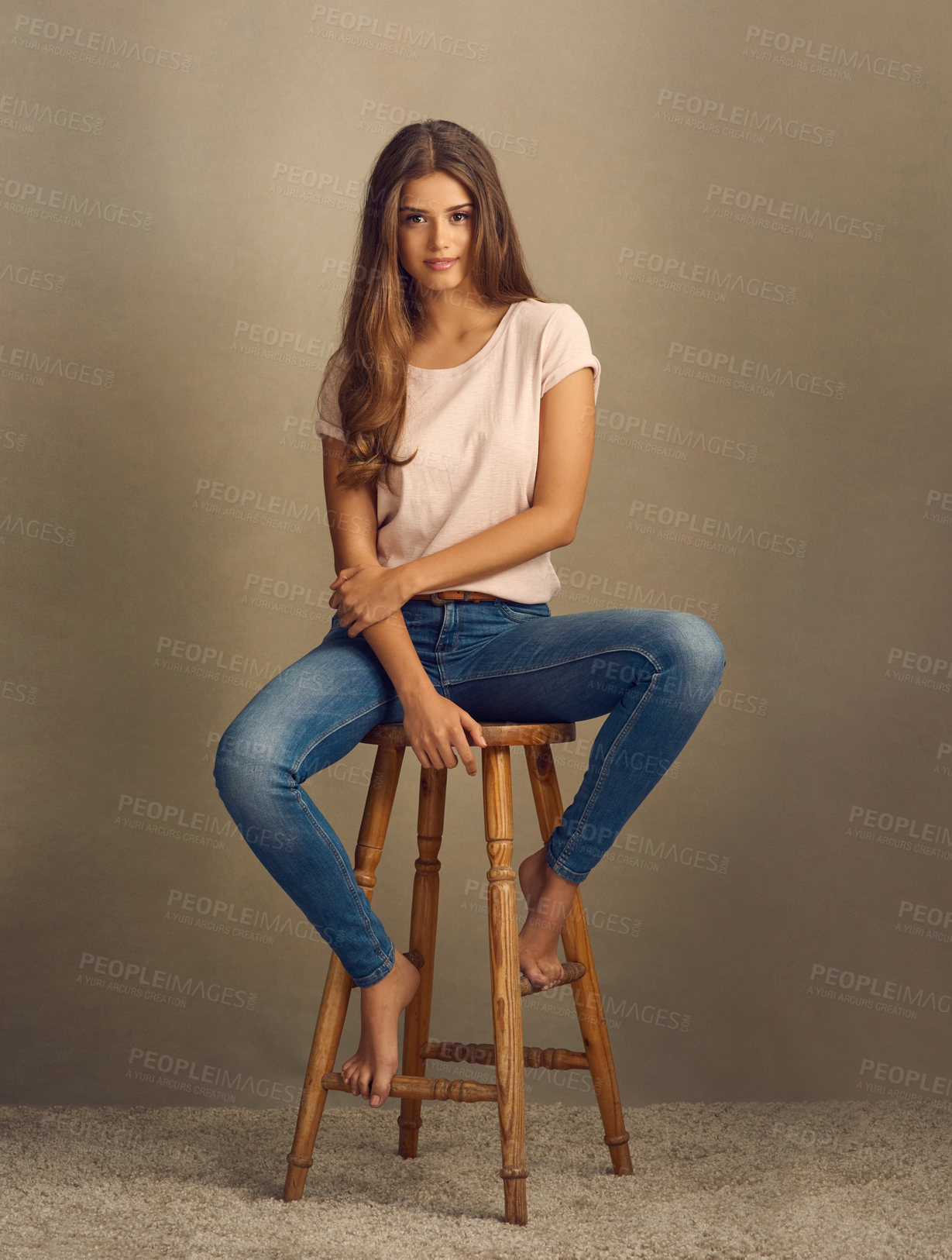 Buy stock photo Studio shot of a beautiful young woman sitting on a stool against a plain background