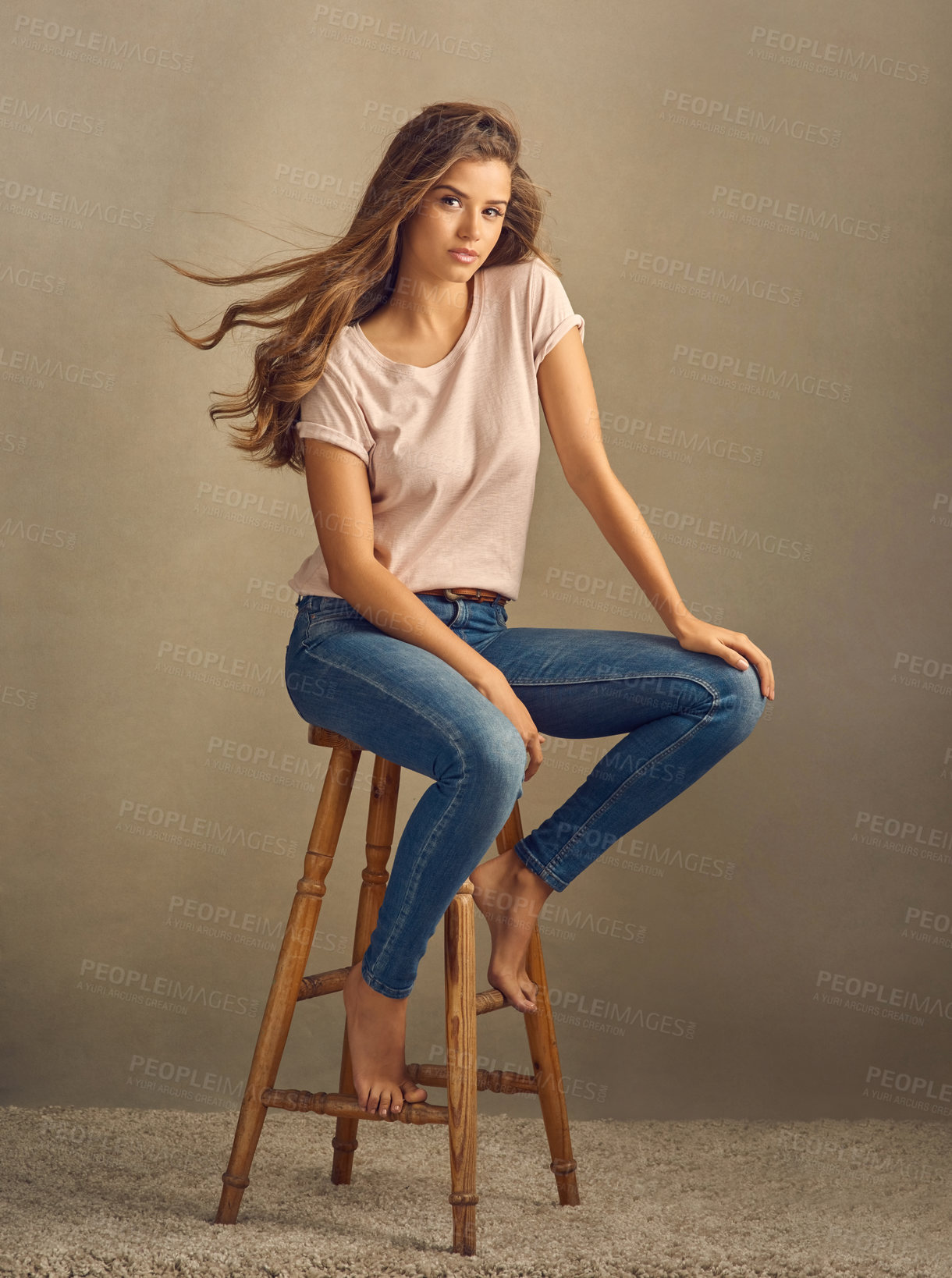 Buy stock photo Woman, hair care and studio portrait with wind for growth, textures and casual fashion on stool. Model girl, chair and hairstyle with breeze for, shampoo, clean scalp and clothes by brown background