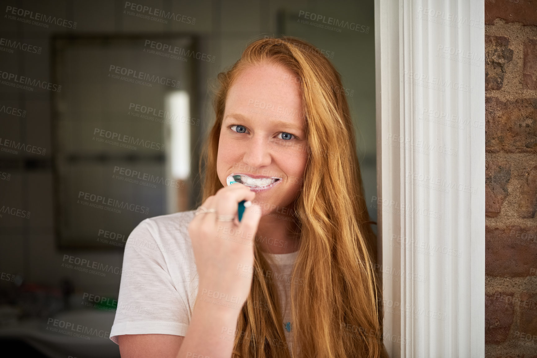 Buy stock photo Shot of a young woman brushing her teeth at home