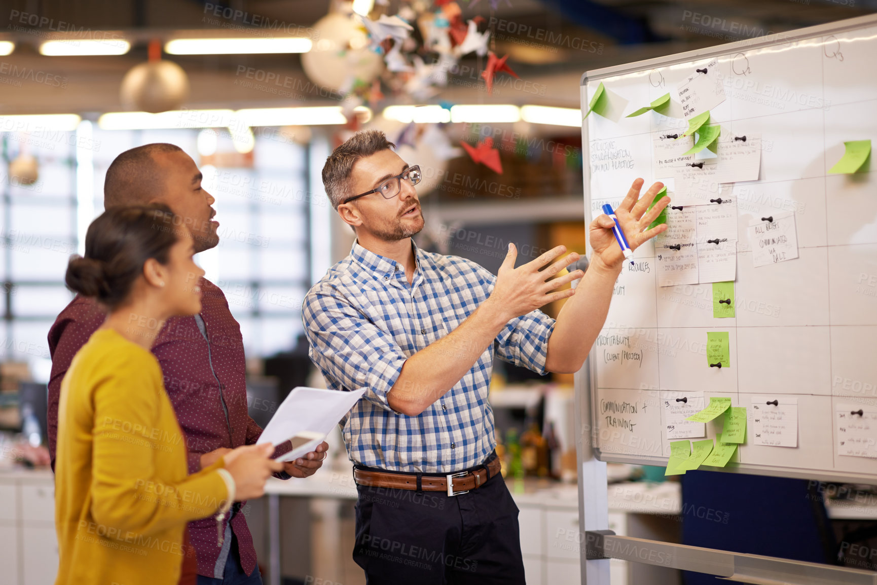 Buy stock photo Shot of a group of coworkers brainstorming at a whiteboard