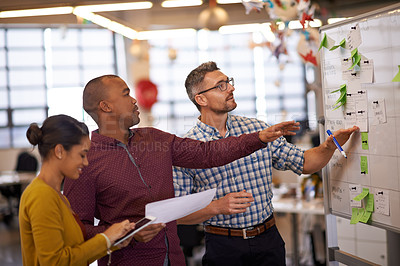 Buy stock photo Shot of a group of coworkers brainstorming at a whiteboard