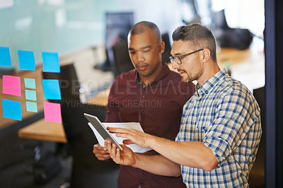 Buy stock photo Shot of two coworkers going over documents together