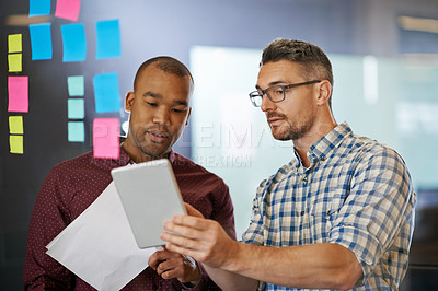 Buy stock photo Shot of two coworkers going over documents together