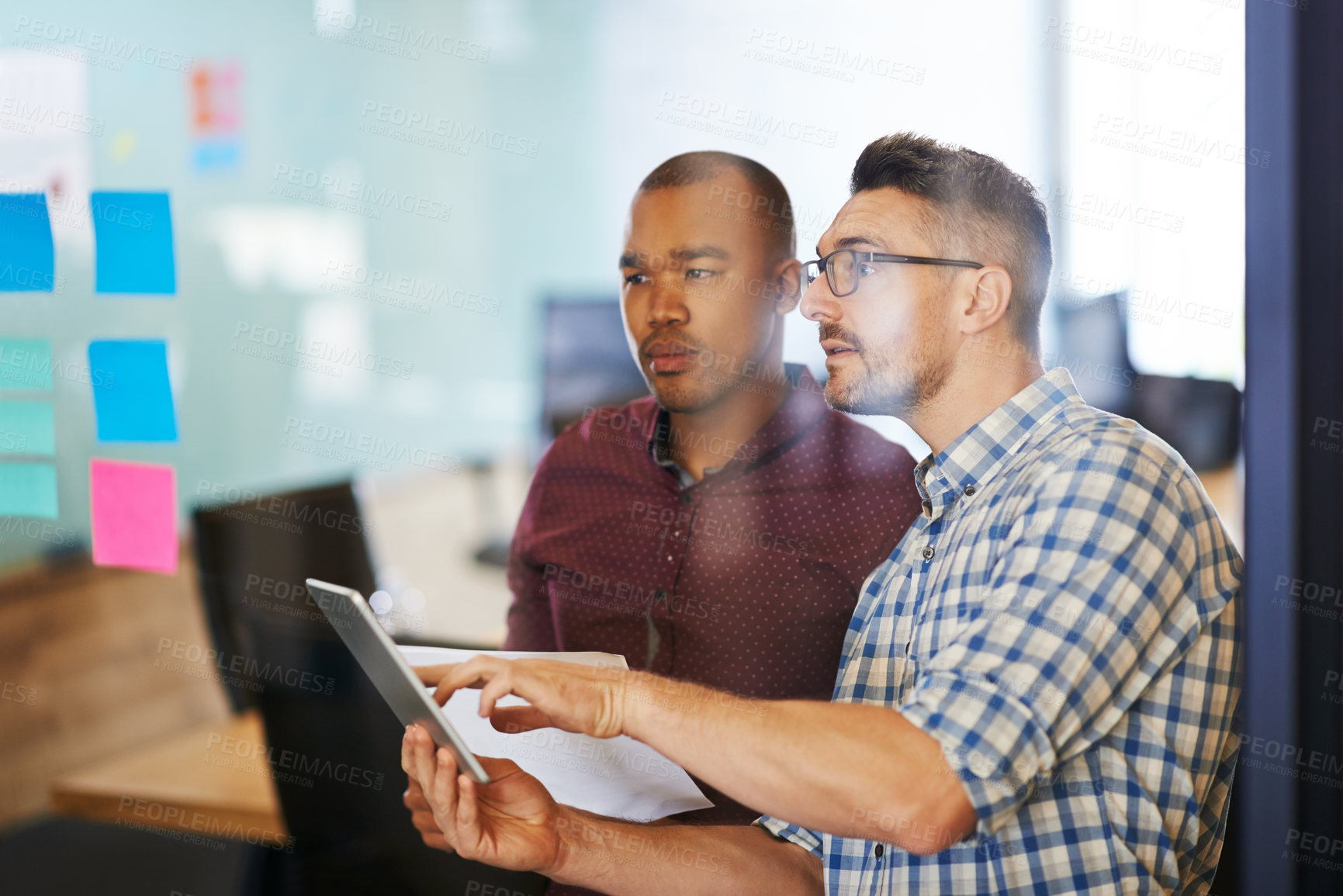 Buy stock photo Shot of two coworkers going over documents together