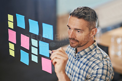 Buy stock photo Shot of a male designer working on a glass wall in the office