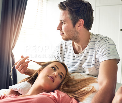 Buy stock photo Shot of a young couple relaxing together on the bed at home