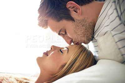 Buy stock photo Shot of an affectionate young kissing his girlfriend’s forehead in the bedroom