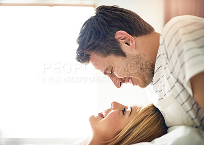 Buy stock photo Shot of an affectionate young couple gazing into each others eyes in the bedroom