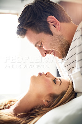 Buy stock photo Shot of an affectionate young kissing in the bedroom