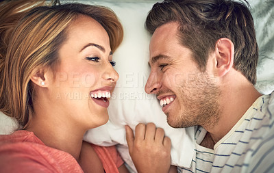Buy stock photo Shot of a happy young couple lying face to face with each other in bed