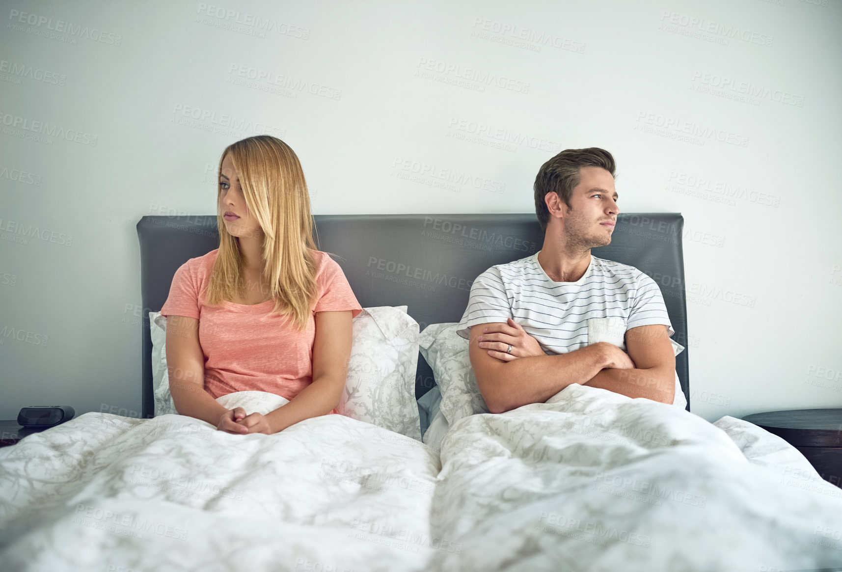 Buy stock photo Shot of a young couple ignoring each other in bed