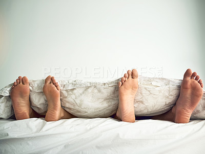 Buy stock photo Shot of a couple’s feet poking out from under the bed sheets