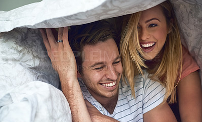 Buy stock photo Shot of a happy young couple having fun under a duvet in bed