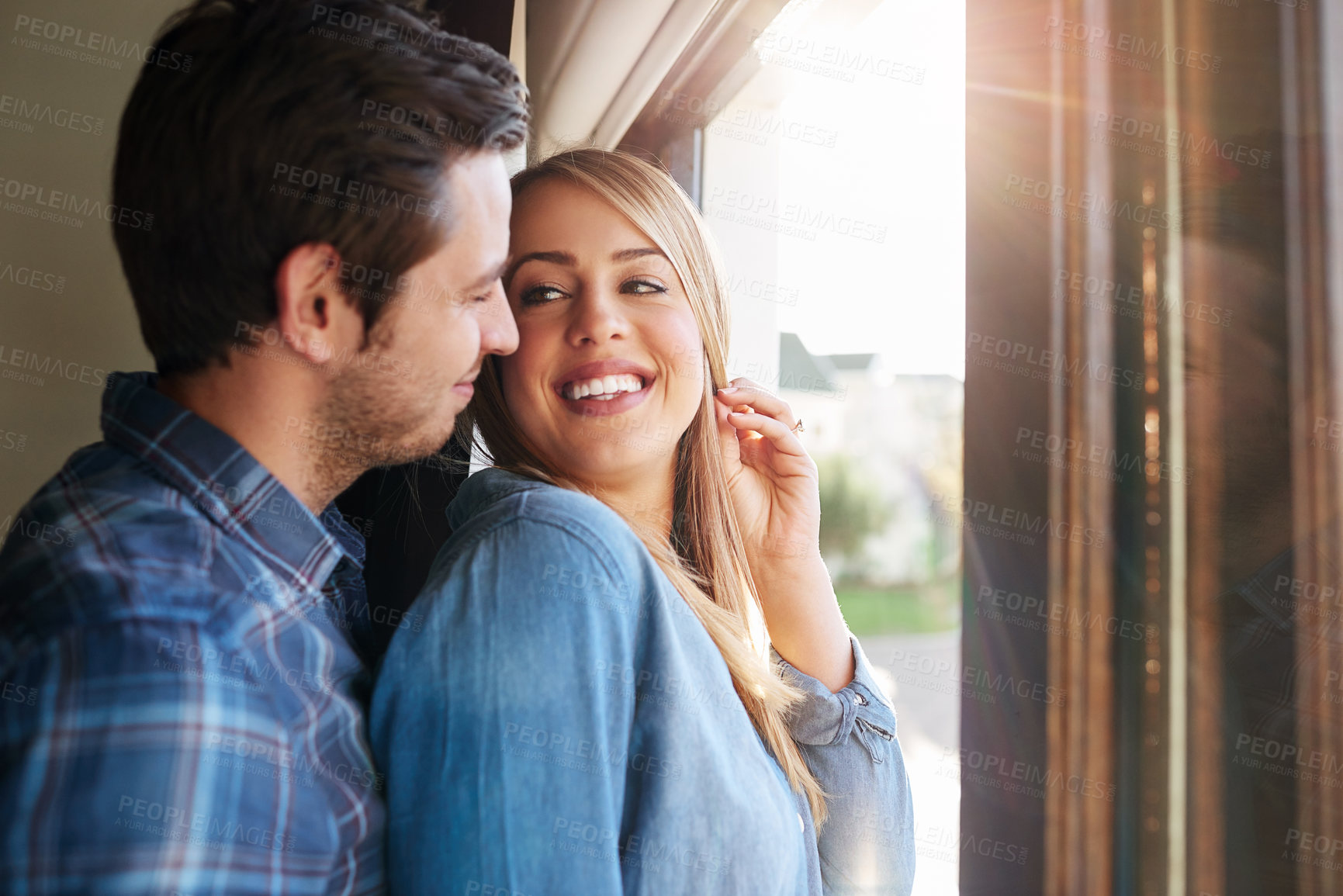 Buy stock photo Cropped shot of an affectionate young couple standing at a window in their home