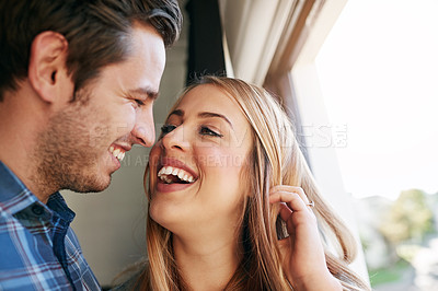 Buy stock photo Cropped shot of an affectionate young couple standing at a window in their home