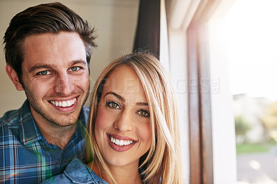 Buy stock photo Cropped portrait of an affectionate young couple standing at a window in their home