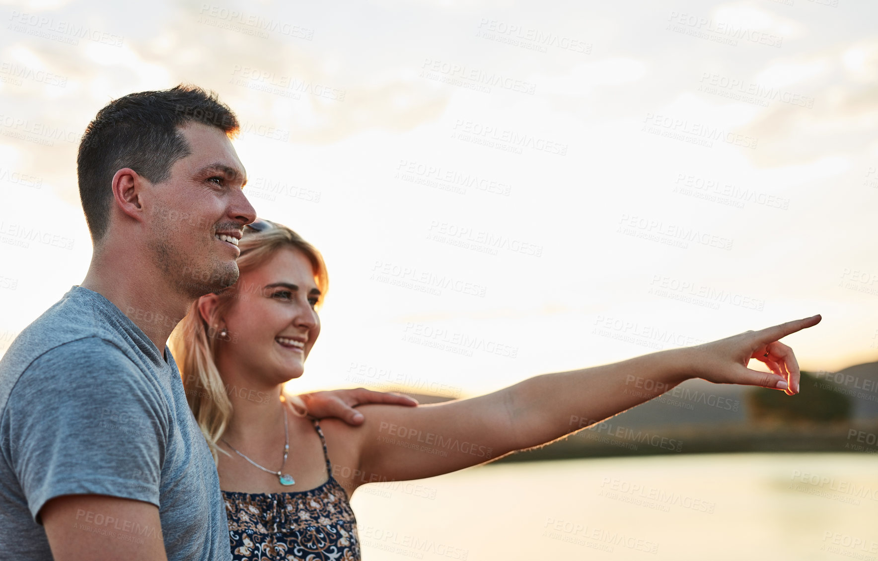 Buy stock photo Holiday, date and couple pointing at lake with romance, nature or outdoor bonding together. Love, man and woman with view of river for adventure, vacation and embrace on mockup in cloudy sky