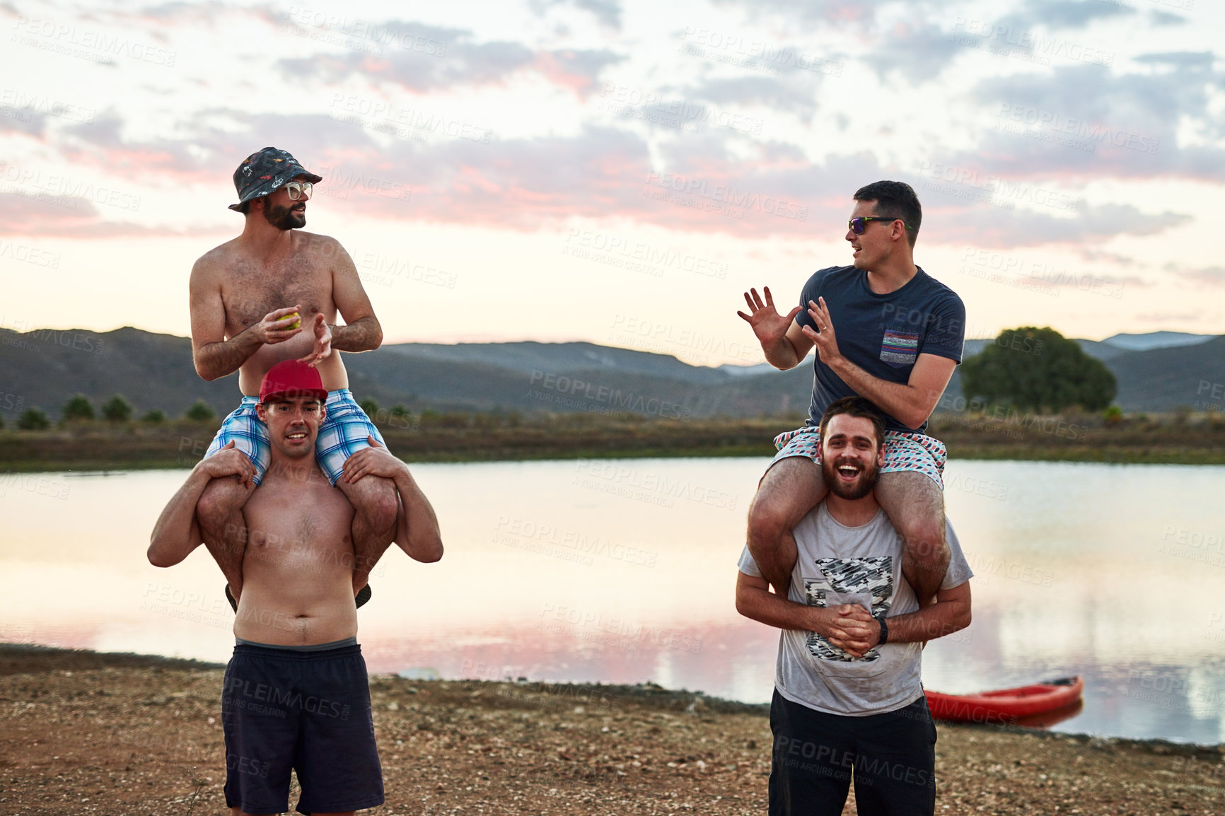 Buy stock photo Lake, friends and group of men on shoulder for outdoor adventure holiday together with smile. Sunset, nature and playful people relax at river with support, bonding and fun at  water for vacation