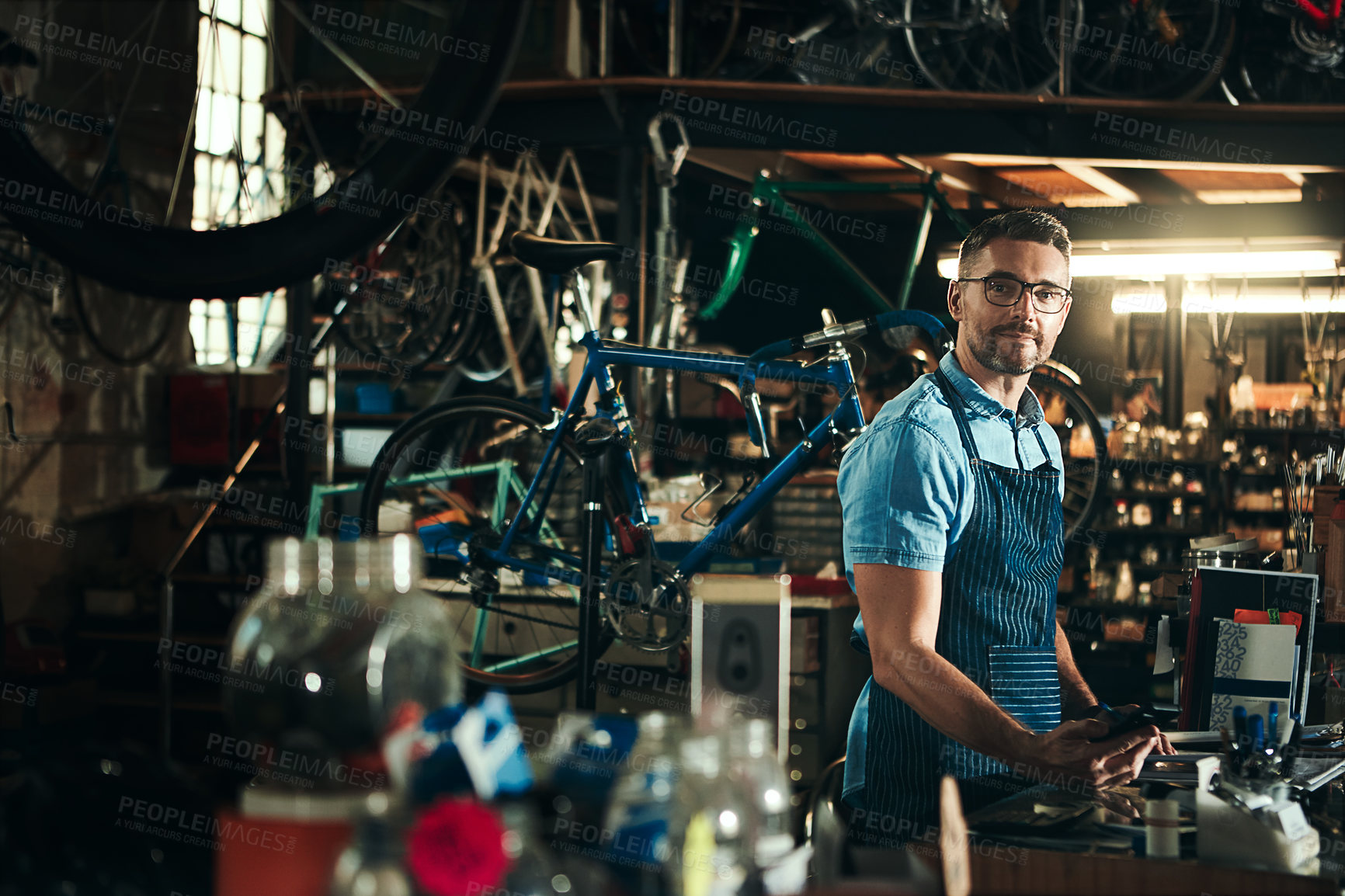 Buy stock photo Man, portrait and bicycle mechanic with tools in small business for fix, repair or maintenance. Young male person, cycle engineer or bike technician with equipment for job or career at workshop