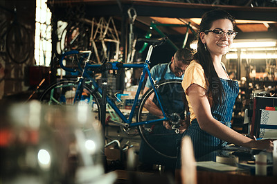 Buy stock photo Portrait, smile and woman working in bicycle shop for repair  in store or cycling workshop. Face, bike mechanic and confident female person, professional or technician with happiness and glasses.
