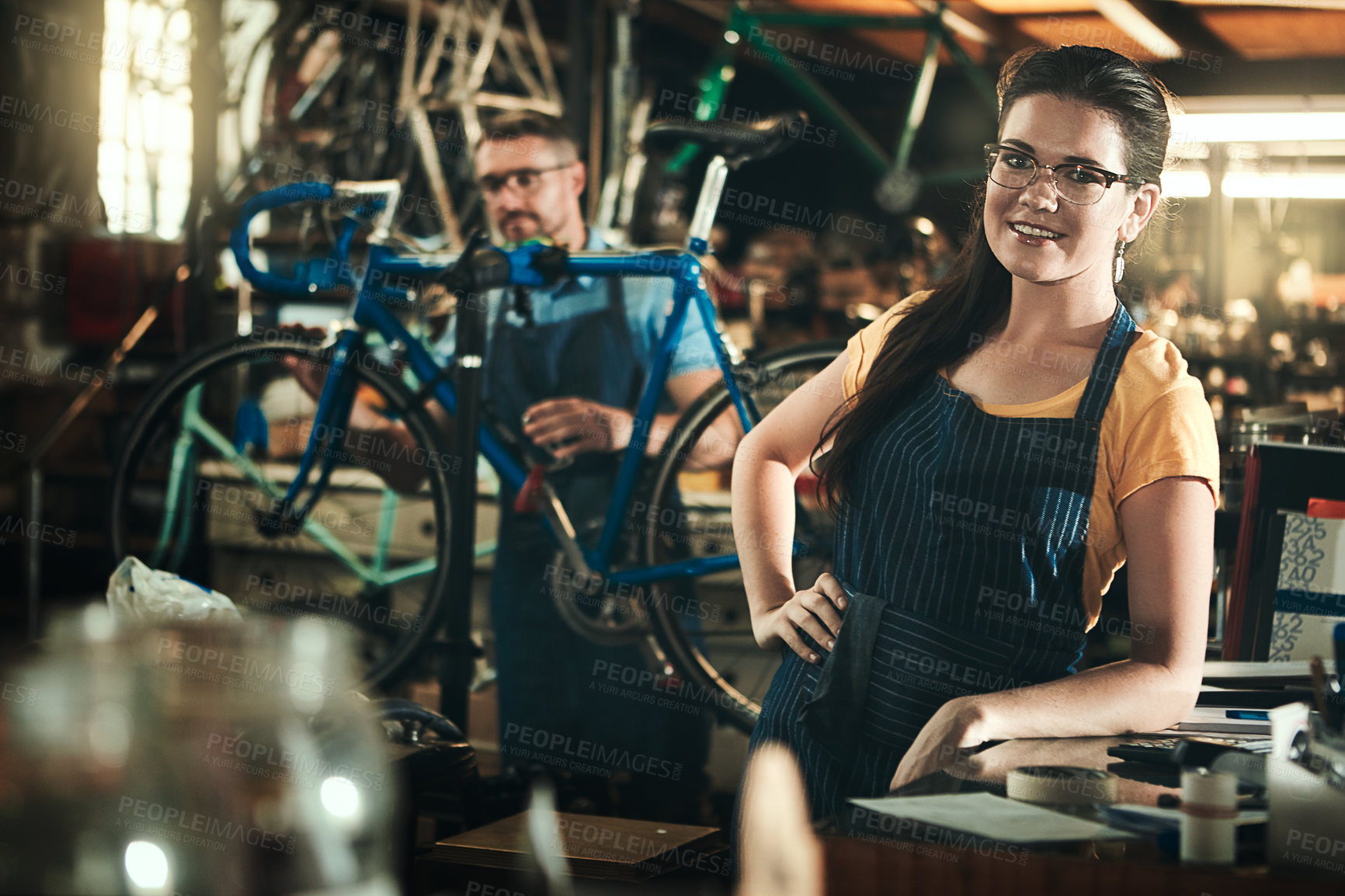 Buy stock photo Portrait, working and smile of woman in bicycle shop, repair store or cycling workshop. Face, bike mechanic and confident person, professional or technician standing with glasses in small business.